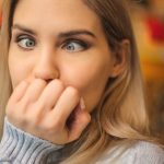A blonde woman makes a silly face indoors, showcasing a playful and humorous expression.